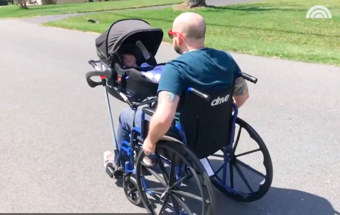 Hombre en silla de ruedas paseando a su bebé