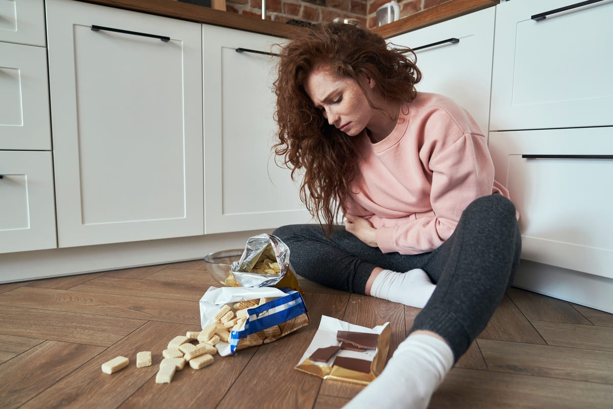 mujer frente a comida chatarra con dolor menstrual