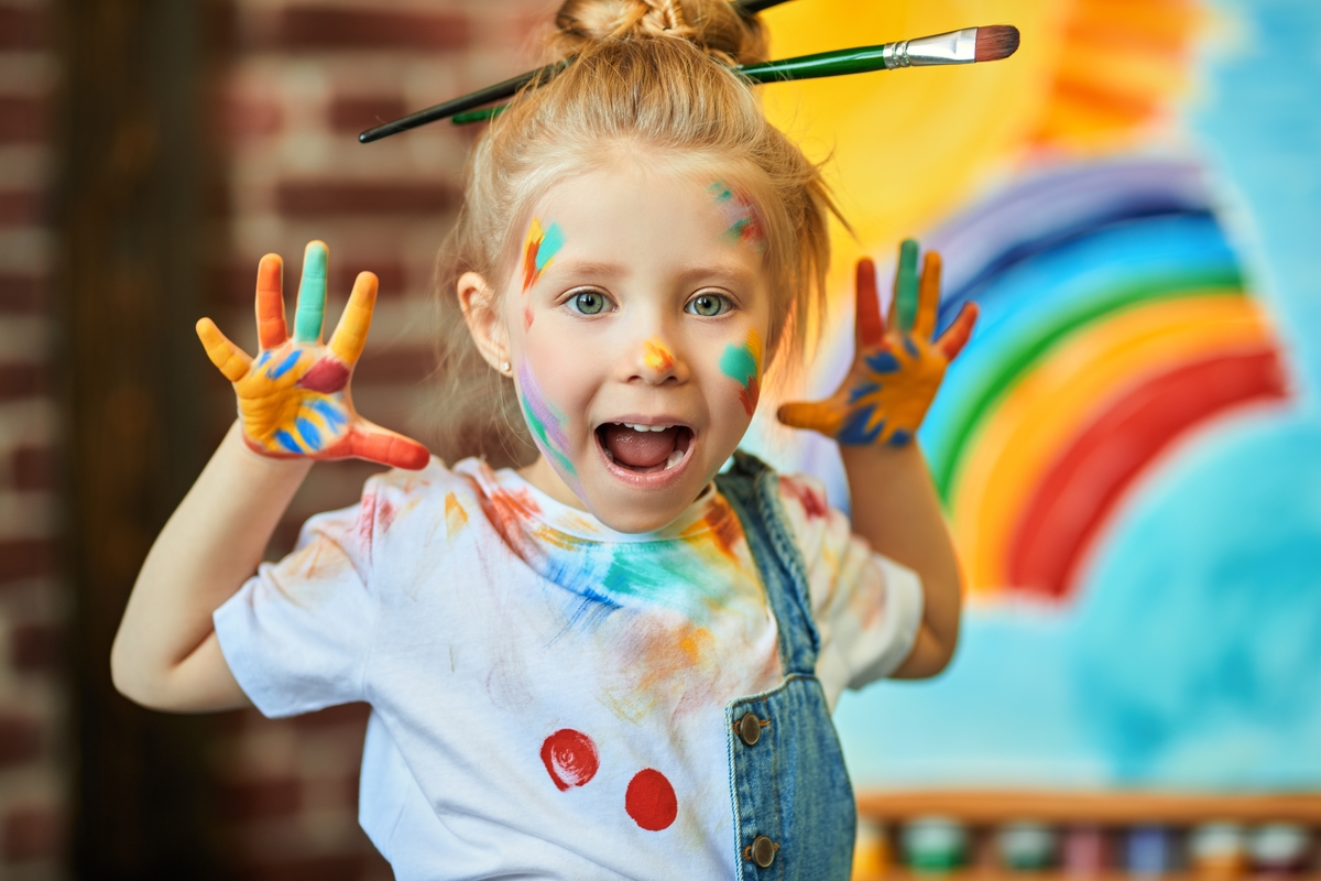 niña pintada y con pinceles frente a su obra