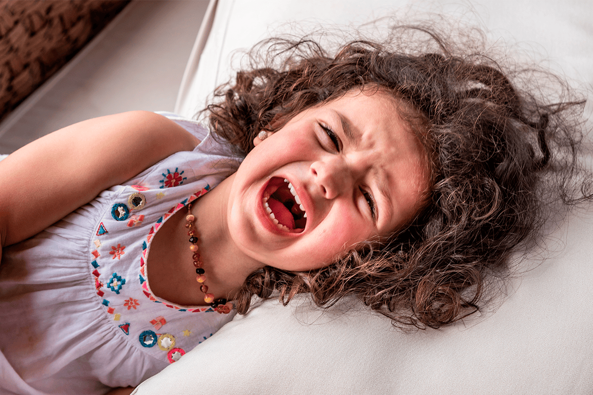 niña de cabello rizado acostada gritando y llorando