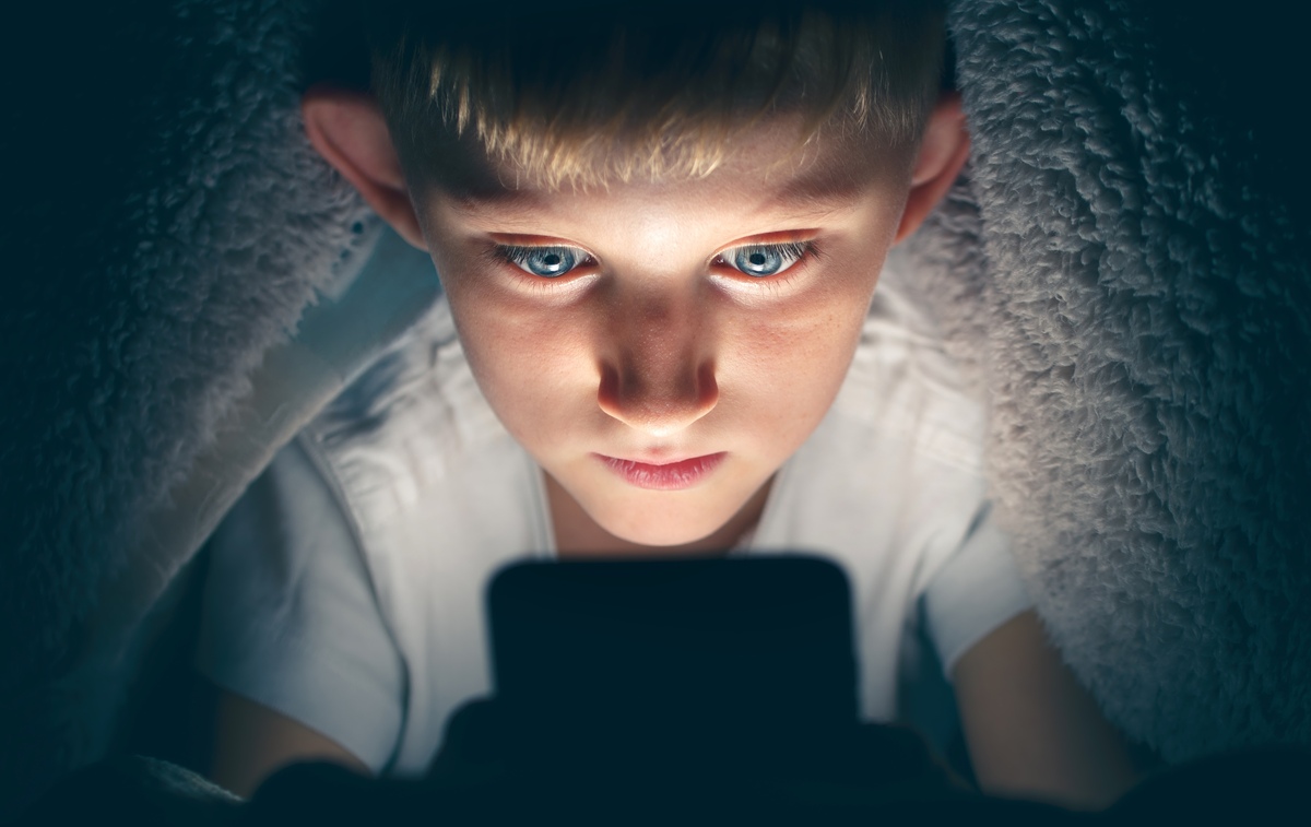 niño oculto leyendo su celular