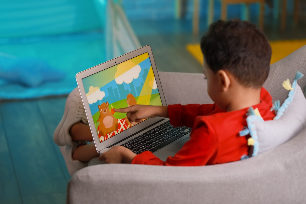 niño tomando una laptop mientras ve caricaturas