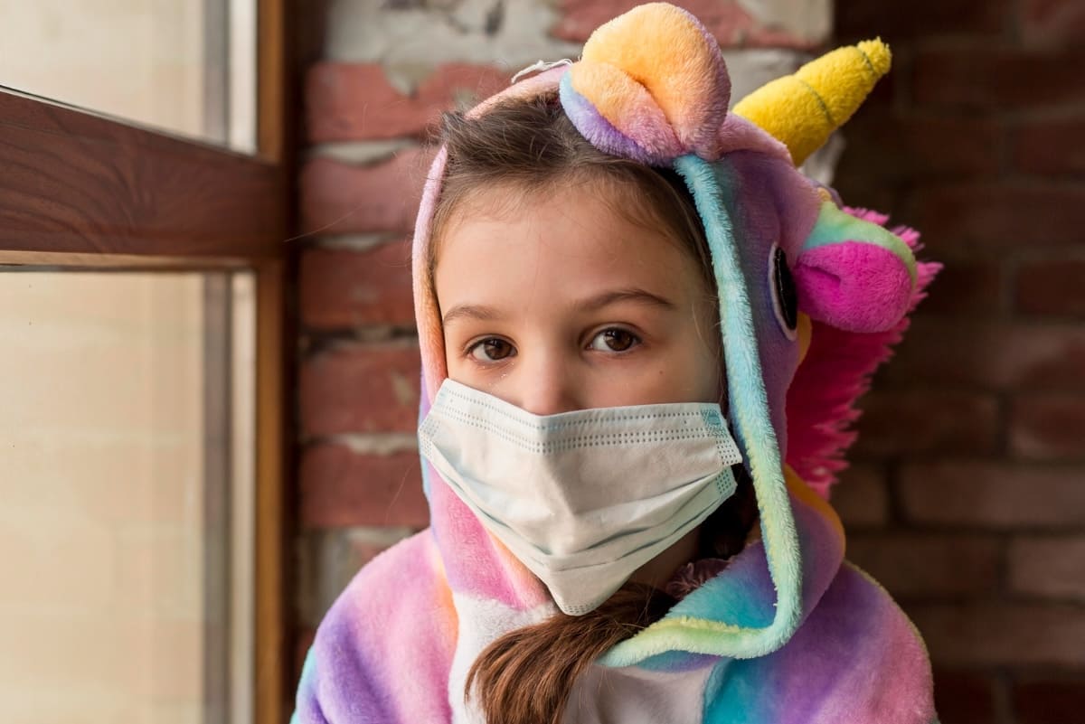 niña enferma con mameluco y cubrebocas