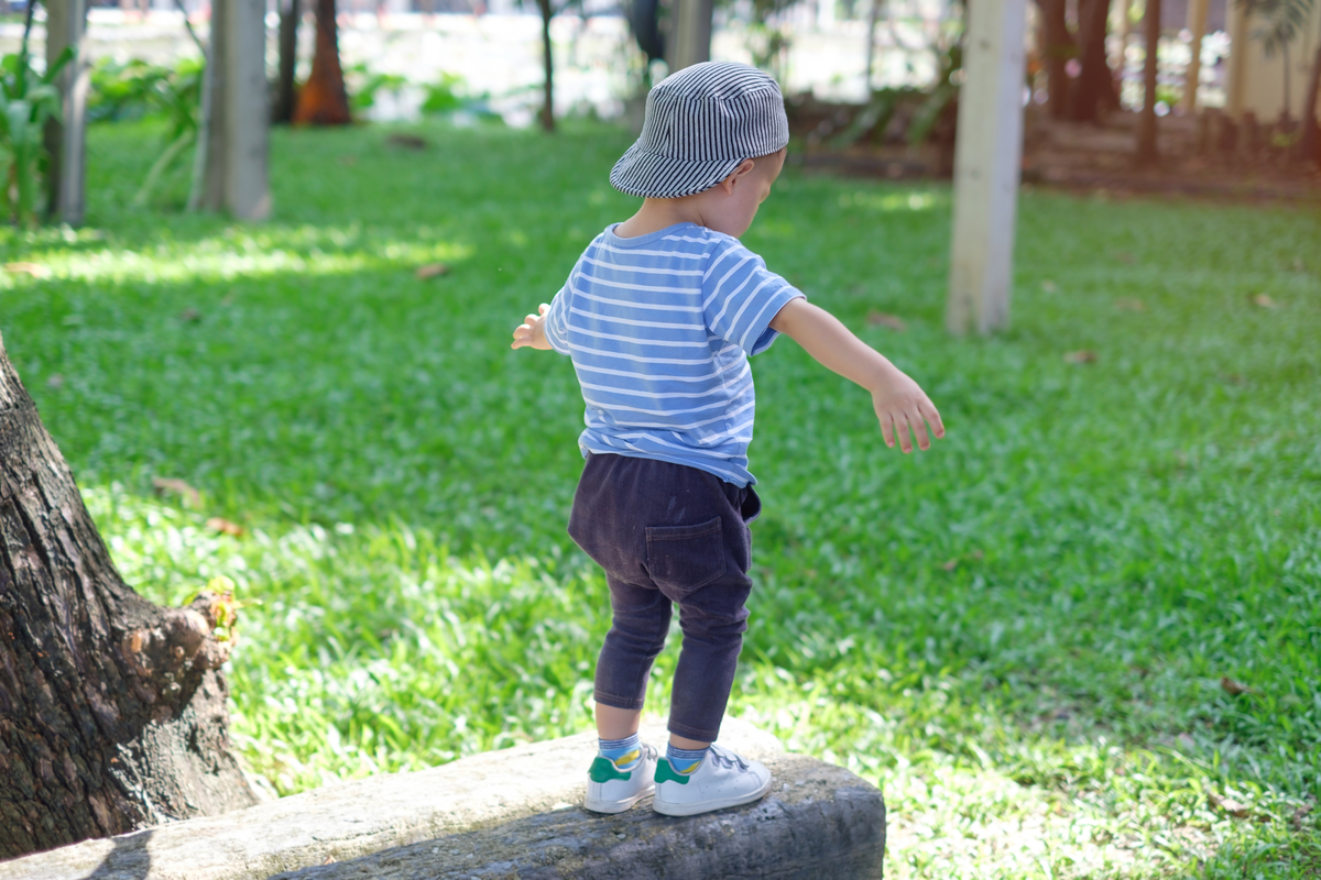 niño pequeño guardando equilibrio en un tronco 