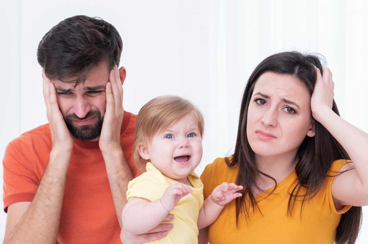 papás estresados con un niño llorando