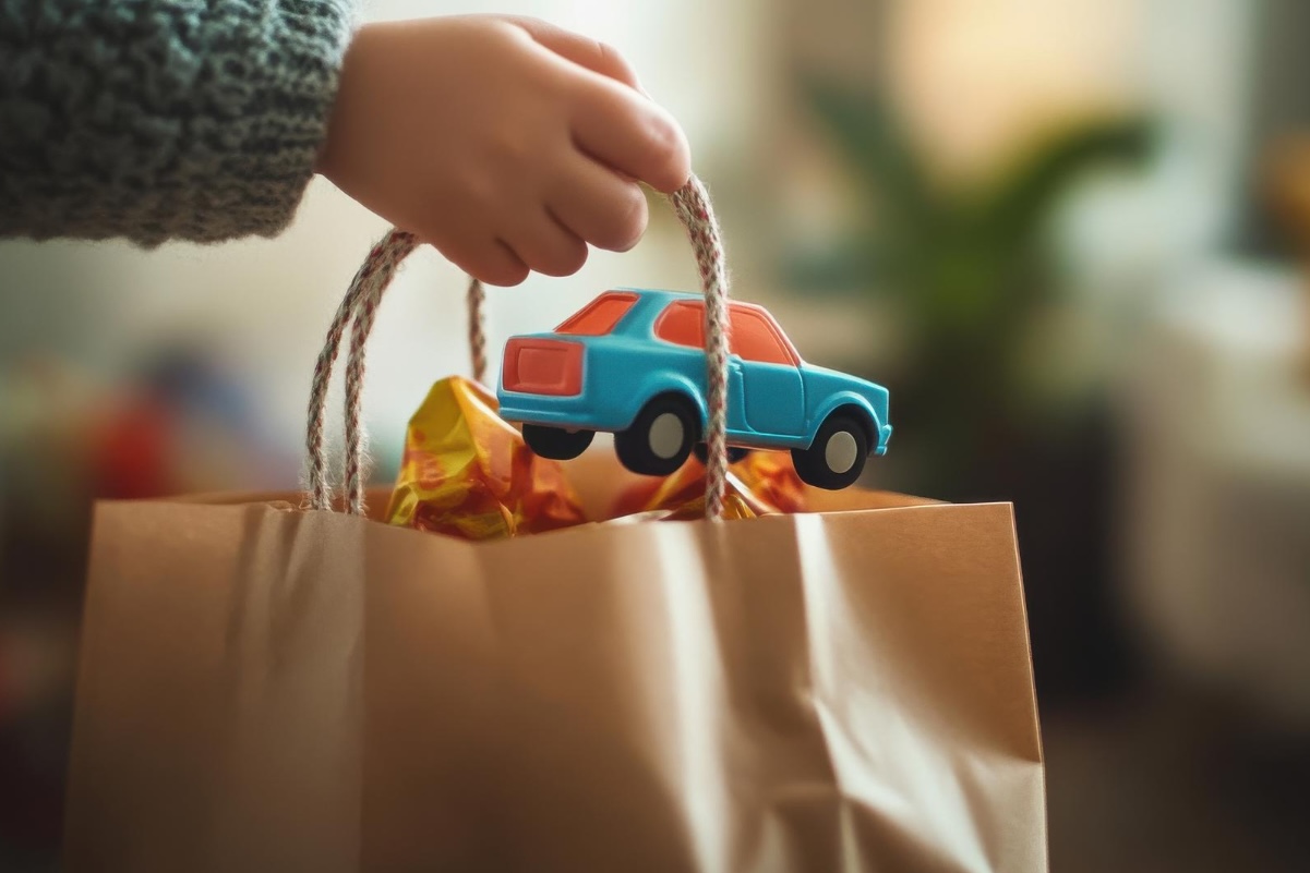 niño sostenindo bolss con juguetes 