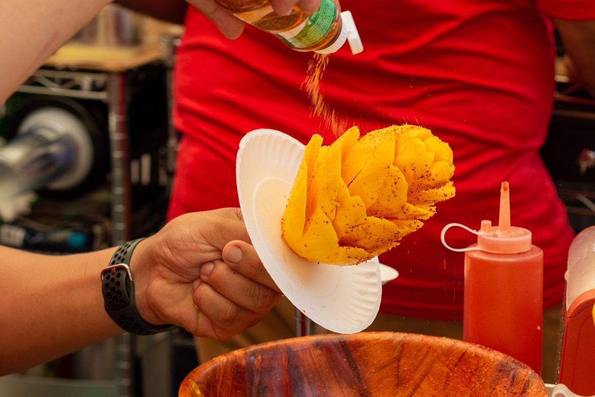 persona preparando un mango tirándole tajín por encima 