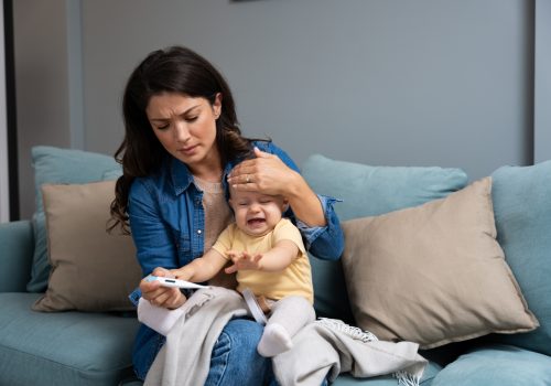 Mother,Measuring,Temperature,Of,Her,Sick,Crying,Baby,Sitting,On