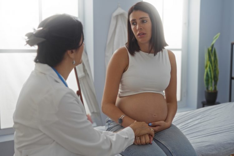 Doctor,Consulting,Pregnant,Woman,In,A,Clinic,Room,While,Discussing